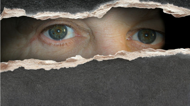 Man looking through hole in wall