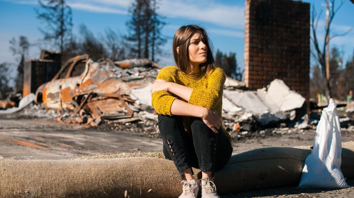 Woman Sitting in Front of Burned Housee
