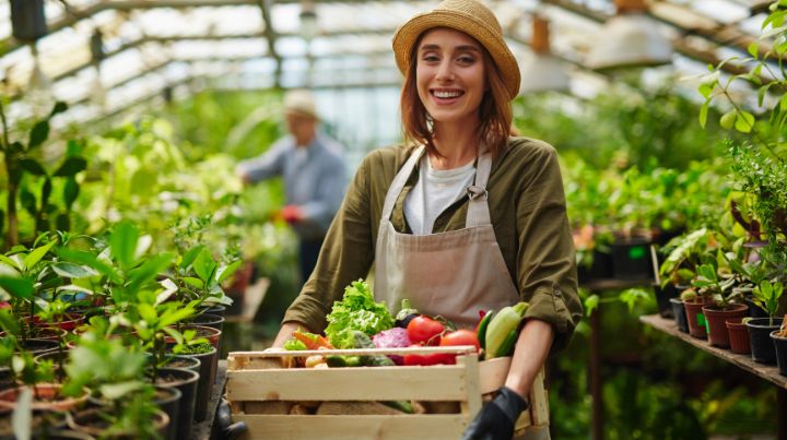 A smiling woman with a basket of fresh vegetables from the garden. 