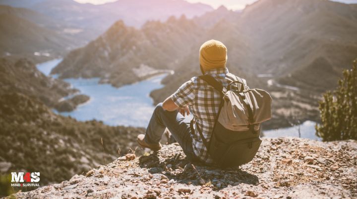 Man sitting on mountain overlooking a lake