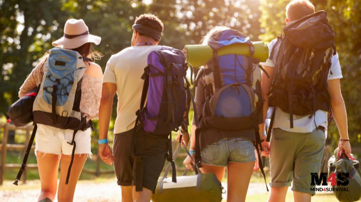 Friends with backpacks walking down a trail.