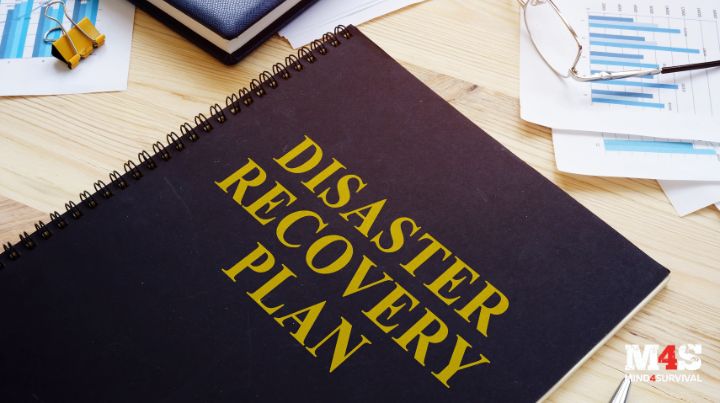 A notebook that says "Disaster Recovery Plan" on the cover sitting on a desk. 