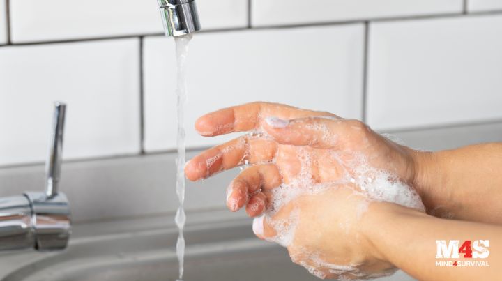 A person washing their hand in the kitchen sink