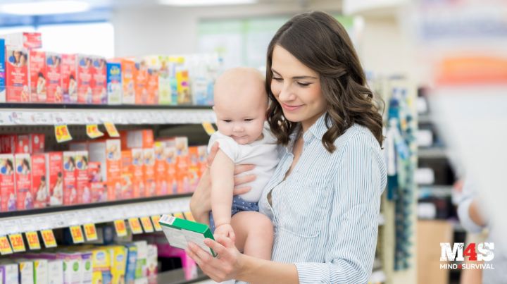 A mom shopping for cold medicine with her baby in her arms